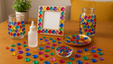 A bright workspace showing colorful flat-back acrylic gems, glue, and decorated jars and frames used for home décor crafts.