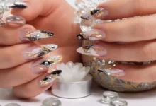 Elegant acrylic nails decorated with black, gold flakes, and gems showcasing acrylic gem durability and long-lasting shine.